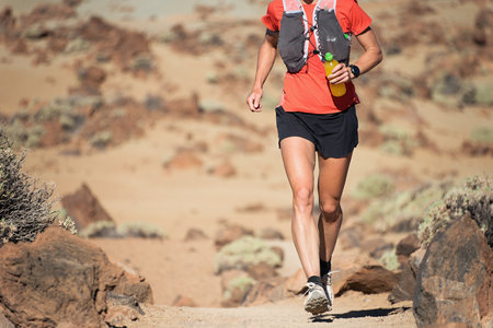 Female athlete runs mountain race with hydration trail vest for running