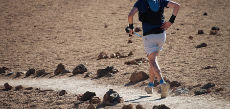 Trail running runner man on endurance run with hydration trail vest on volcano mountain. Ultra...
