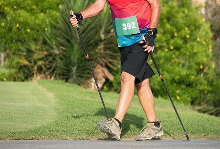 Man practices nordic walking sport on the park with nordic walking polesの写真素材