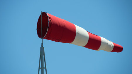 Windsock indicator of wind. Wind cone indicating wind direction and force. Horizontally flying windsock with blue sky in the backgroundの写真素材