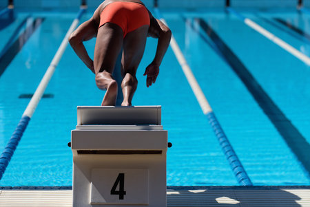 The swimmer jumps from the start block at the start of the raceの写真素材