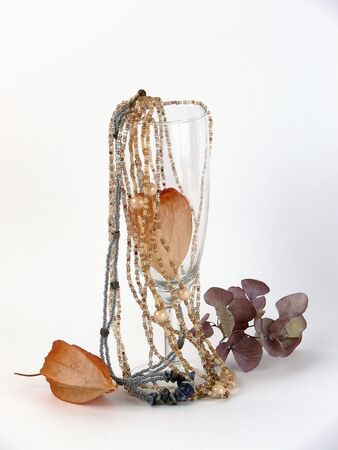 Still life with  beaded necklace, dry flowers and wineglasses on white backgroundの写真素材