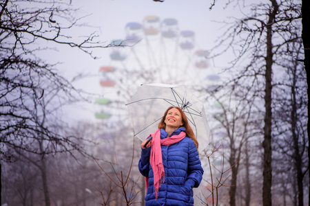 girl in the park stands with an umbrella in front of the ferris wheel and admires natureの写真素材