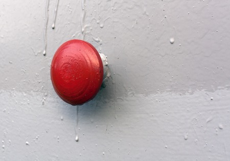 Red button on gray metal wall. Background and texture.の写真素材