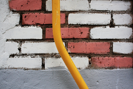 Yellow tube on brick wall. Architectural background.の写真素材