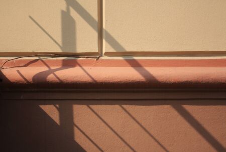Hand rail shadow on orange wall. Architectural backgroundの写真素材