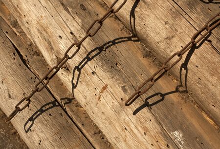 Rusty metal chain on log barn wall. Abstract background