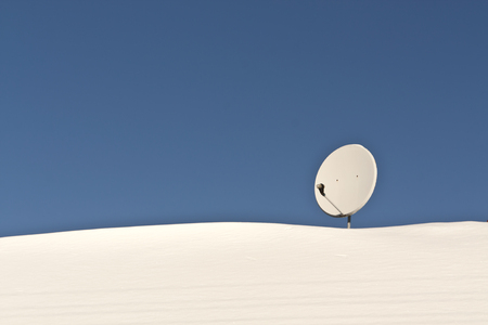 Sattelite antenna on snowy roof. Seasonal background.の写真素材