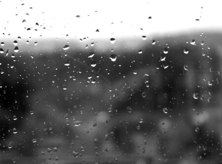 Raindrops on window in black and white. Seasonal background and texture for design.