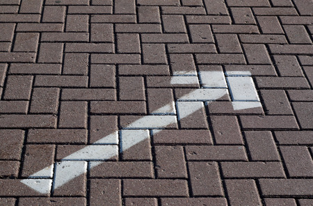 White painted arrow on pavement. Signs and symbols.