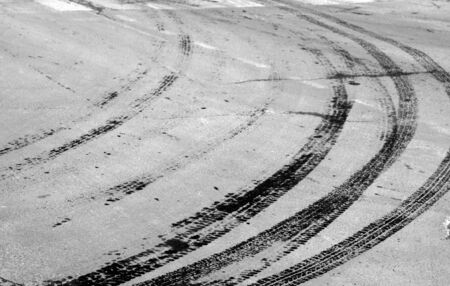 Wet tyre tracks on dirty asphalt road in black and white. Abstract background and pattern.の写真素材