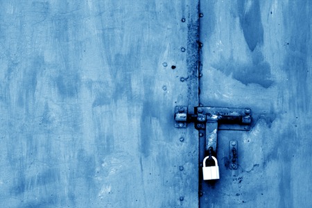 Old padlock on metal gate in navy blue tone. Abstract background and texture.の写真素材