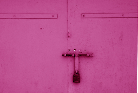 Old padlock on metal gate in pink color. Abstract background and texture.の写真素材