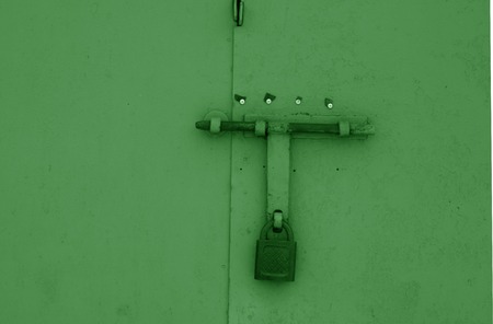Old padlock on metal gate in green color. Abstract background and texture.の写真素材