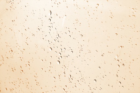 Blured water drops on window in orange tone. Seasonal background texture for design.の写真素材