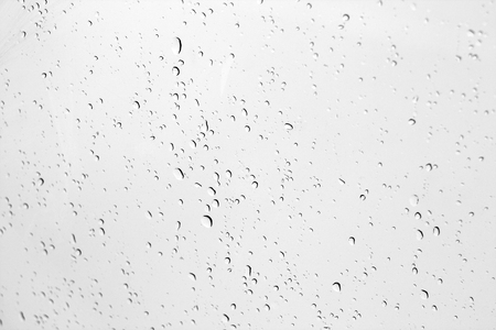 Blured water drops on window in black and white. Seasonal background texture for design.の写真素材