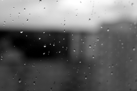 Rain drops on window with blured background in black and white. Seasonal background texture for design.の写真素材
