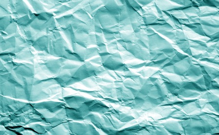 Crumpled sheet of paper in cyan color. Abstract background and texture for design.の写真素材