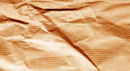 Crumpled sheet of paper with blur effect in orange tone. Abstract background and texture for design.の写真素材