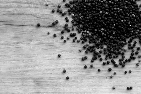 Black pepper close-up on wooden desk in black and white. Abstract background and texture for design.