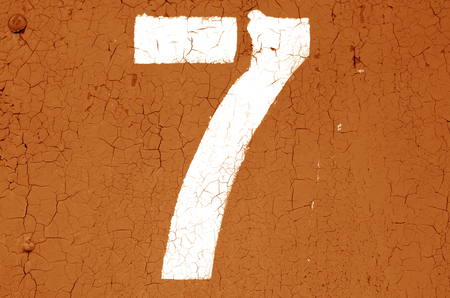 Number 7 in stencil on metal wall in orange tone. Abstract background and texture for design.