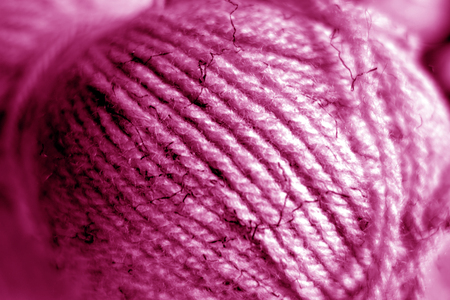 Yarn ball close-up with blur effect in pink tone. Abstract background and texture for design.
