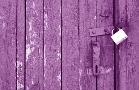 Old padlock on wooden gate in purple tone. Abstract background and texture.の写真素材