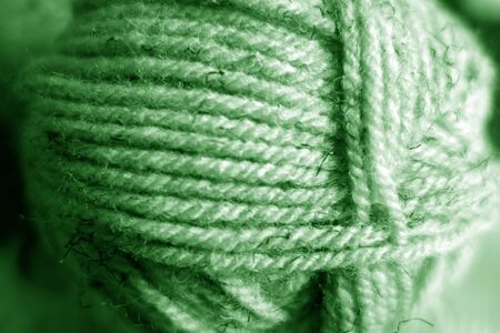 Yarn ball close-up with blur effect in green tone. Abstract background and texture for design.の写真素材