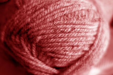 Yarn ball close-up with blur effect in red tone. Abstract background and texture for design.