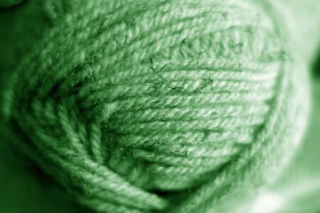Yarn ball close-up with blur effect in green tone. Abstract background and texture for design.の写真素材