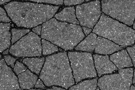 Damaged asphalt surface in black and white. Abstract background and texture for design.の写真素材