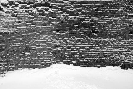 Old black and white brick wall and snow. Architectural and seasonal backgroundの写真素材