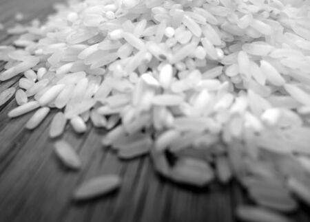 White rice isolated on wooden board with blur effect in black and white. Food and ingredients background.の写真素材