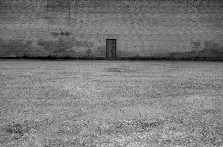 Lonely wooden door on brick wall. Conceptual background               の写真素材
