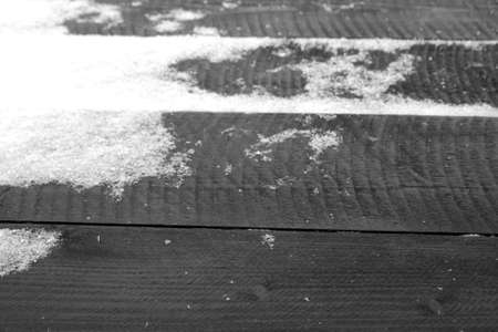 Snow on wooden boarded terrace in black and white. Natural background and texture for design.
