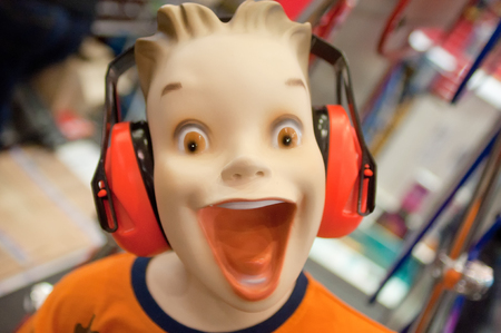 portrait of a dummy head amazed boy with open mouth and construction headphones on the headの写真素材