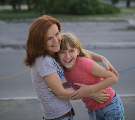 young pretty attractive caucasian mother having fun with teenage daughter hugs smiling cuddlingの写真素材
