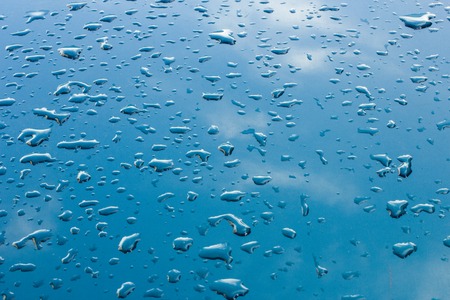 drops of water glisten in the sun on glossy metallic surfaceの写真素材