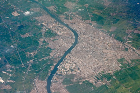 aeral shot of a small town with river flow across and green fiels aroundの写真素材
