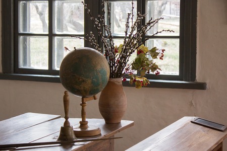 old vintage school with wooden tables, ancient globe and vase with flowersの写真素材