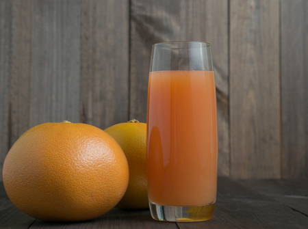 two grapefruits with glass of juice with wooden backgroundの写真素材