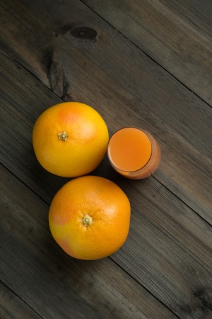 two grapefruits with glass of juice with wooden background shoot from the topの写真素材
