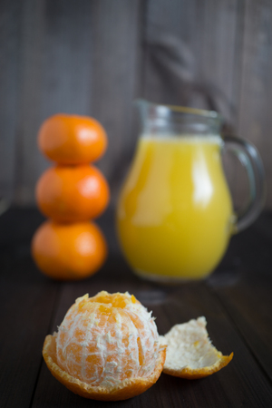 peeled tangerine mandarine with jug of fresh juice and few tangerines as blurred backgroundの写真素材
