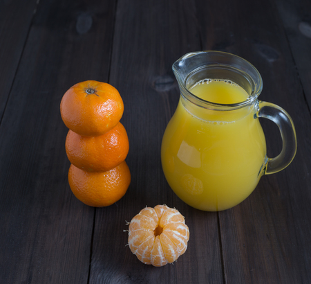 peeled tangerine mandarine with glass of juice and few tangerines with wooden dark backgroundの写真素材