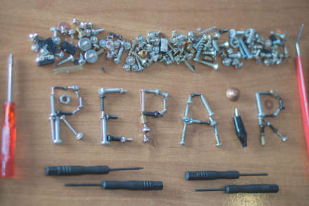 a word repair made of a lot of screws framed with screwdrivers and pincers on a deskの写真素材