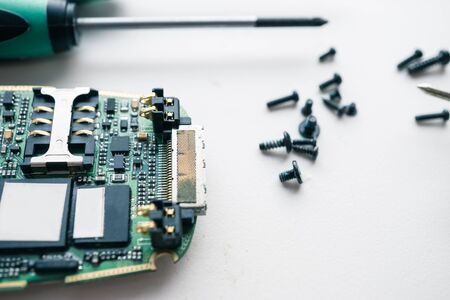 macro shot of disassembled broken smartphone ready for repair. with screws and screwdriversの写真素材