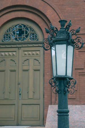 entrance front side of on old brick church with vintage lantern and wooden doorの写真素材
