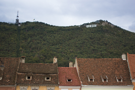 the mountain with inscription sign Brasov alike Hollywood and the red roofs tiles of the old house...