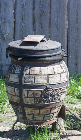 cooking tasty east food in cauldron kettle made of stones. on tandoor of white kaolin clay on open space in the yardの写真素材