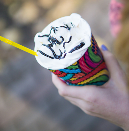 young girl holds in hand multi coloured paper cup of coffeeの写真素材